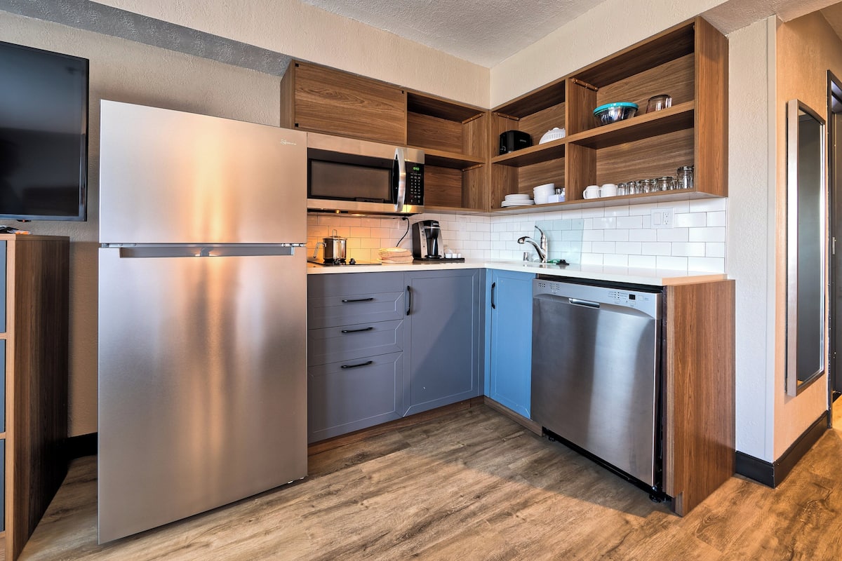 A modern kitchen with stainless steel appliances, wooden cabinets, and a tiled backsplash.
