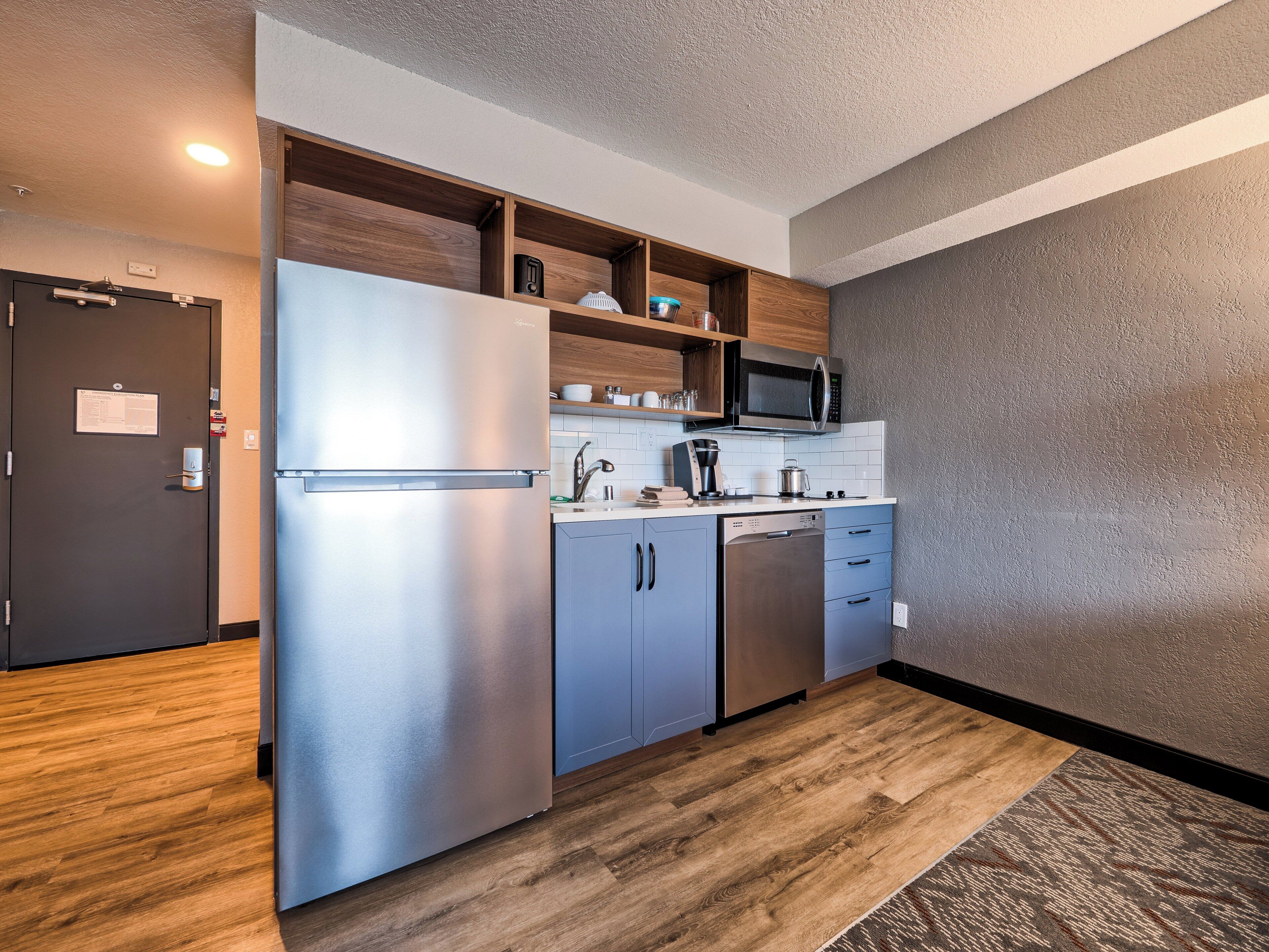 A compact kitchen with a stainless steel refrigerator, a microwave, and a dishwasher.