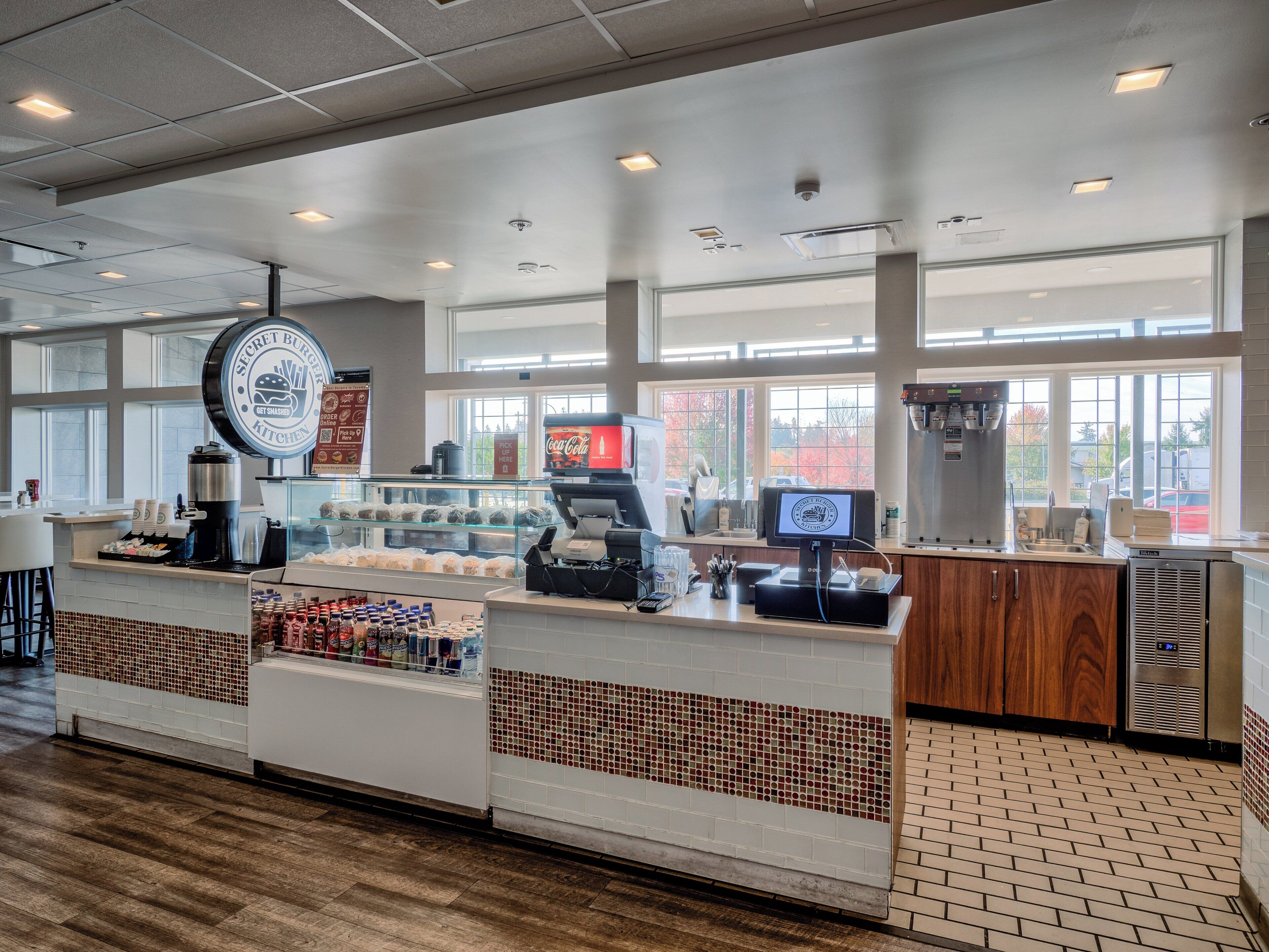 A bakery counter with a coffee machine, a display case with pastries, and a Coca-Cola refrigerator.