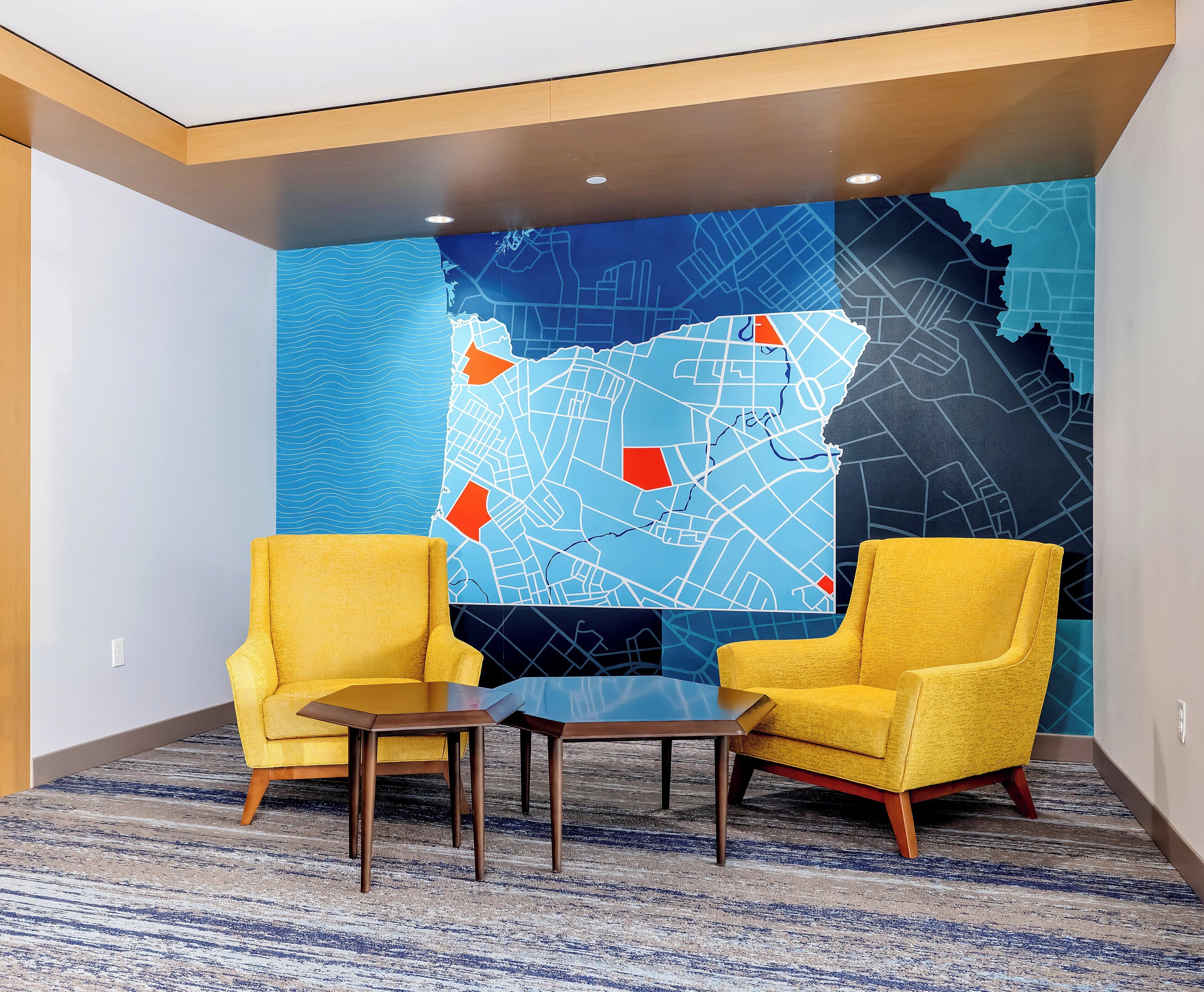 A room with two yellow armchairs, a small table, and a large wall map.