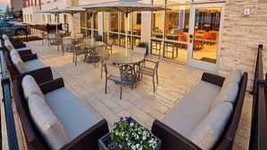 An outdoor patio with wicker furniture, a round table, and umbrellas.
