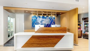 A hotel reception desk with a modern design, a vending machine, and a view of the outside.