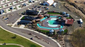 An aerial view of a campground with RV parking, a swimming pool, and a bar area.