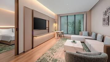 Una habitación de hotel moderna con una cama, un sofá, una mesa de centro, un televisor y un ventanal con vistas a bambú.