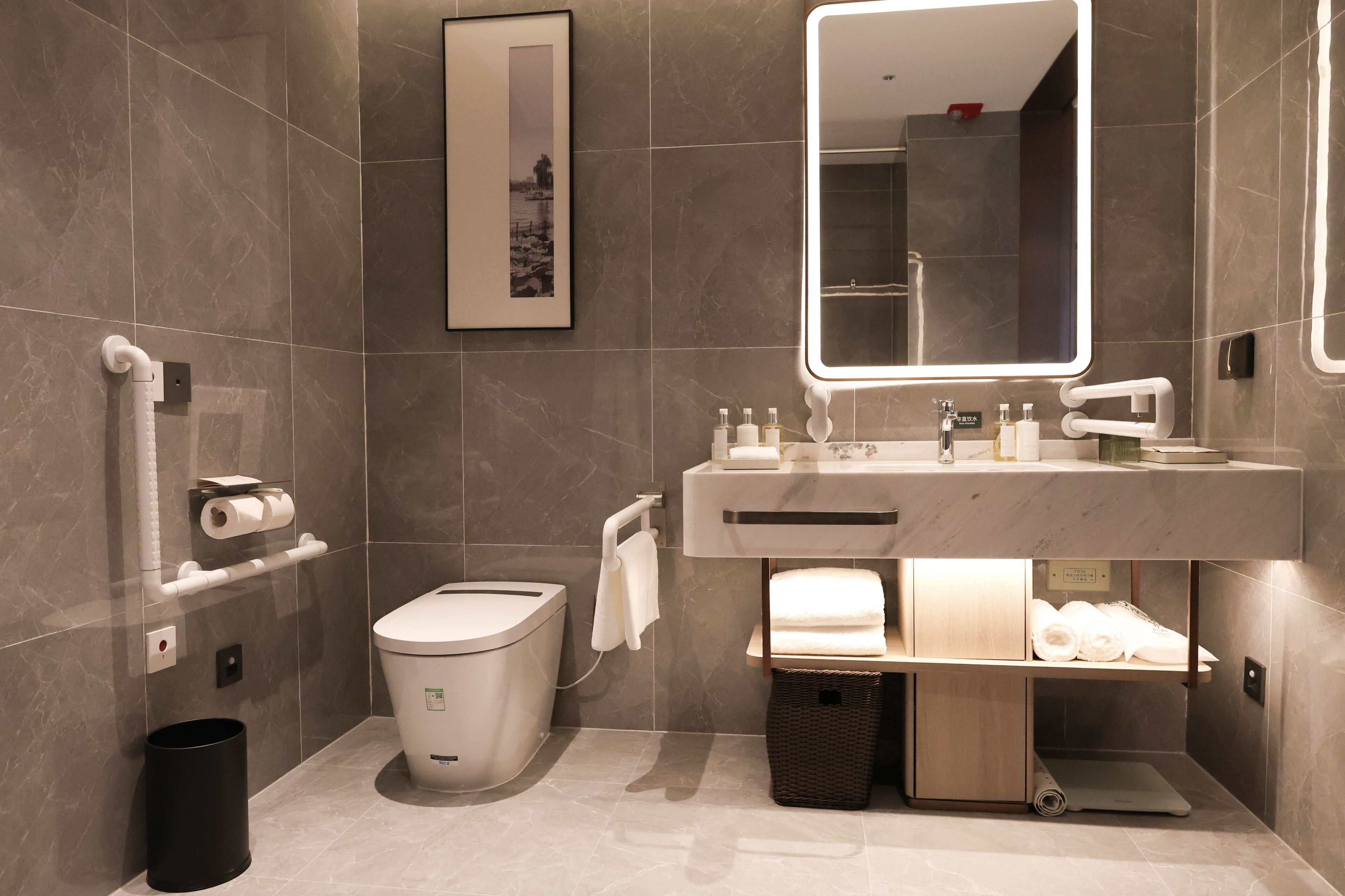 Un baño moderno con inodoro, bidé, lavabo, espejo, toallero y cubo de basura.