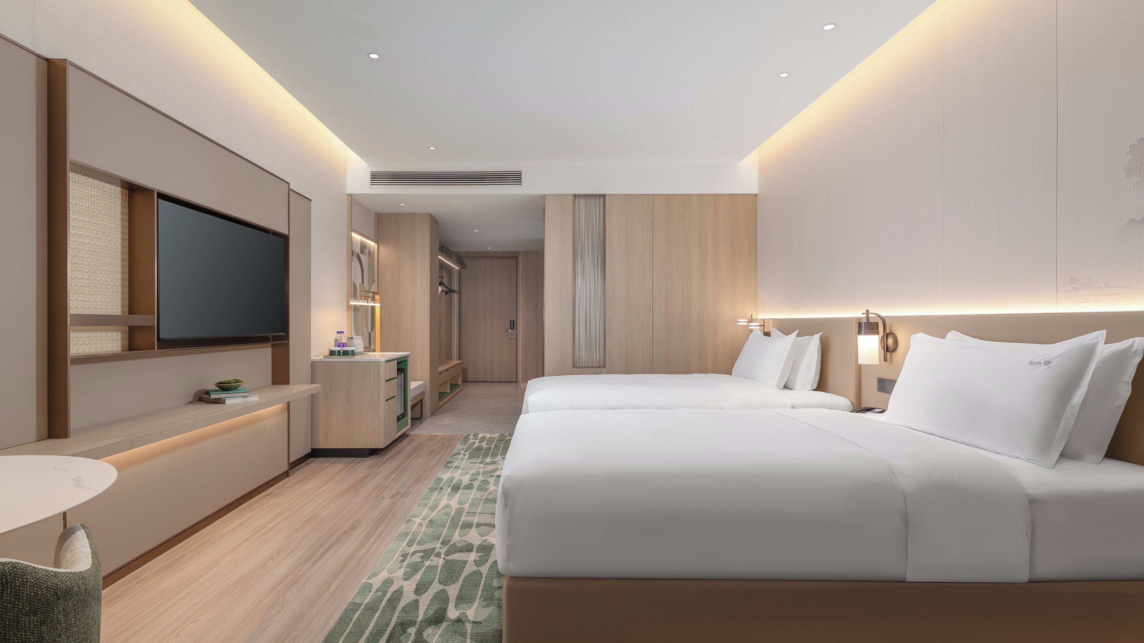 Une chambre d’hôtel moderne, dotée d’un grand lit, d’un bureau et d’une télévision.