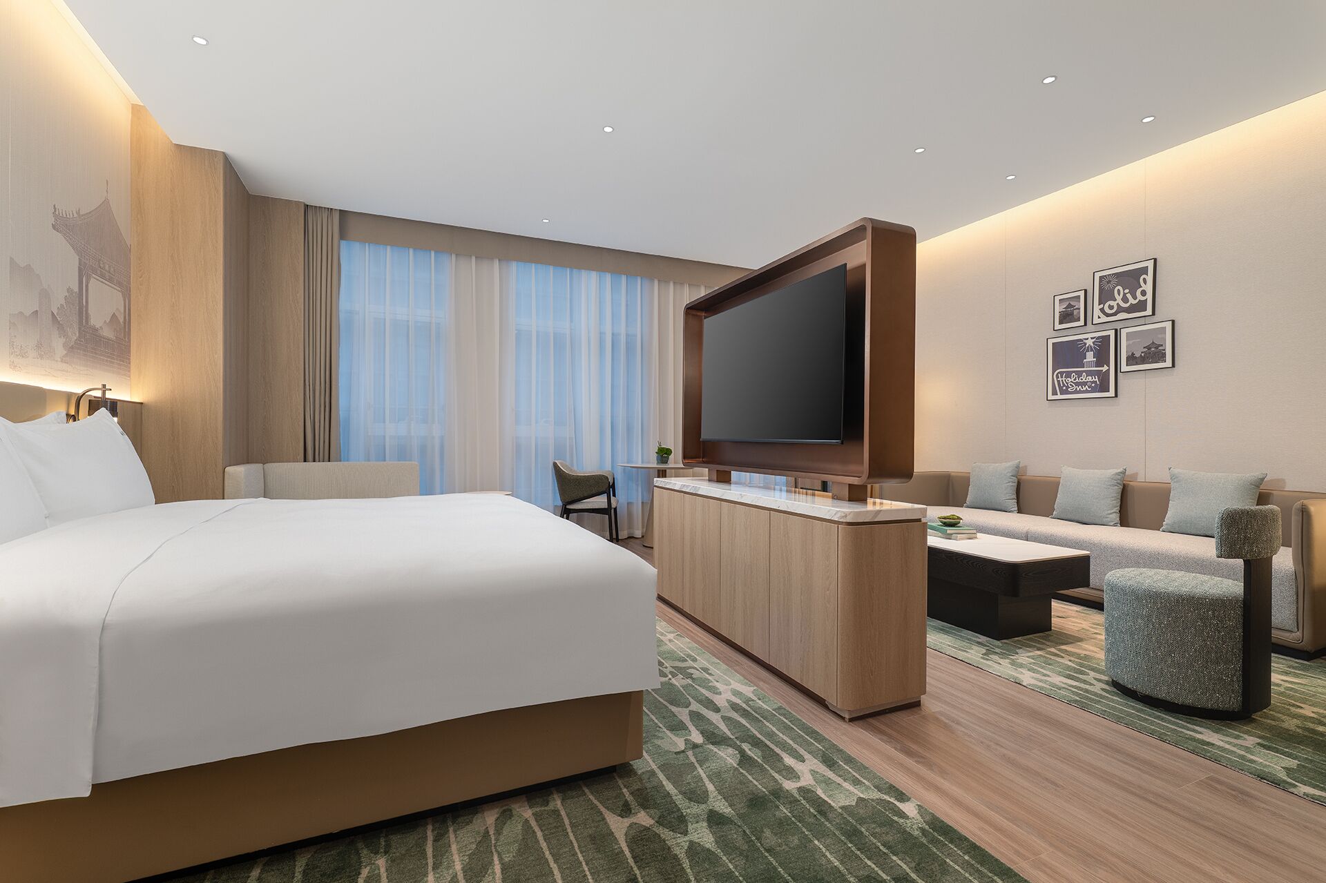 A modern hotel room with a large bed, a flat-screen TV, a sofa, and a small table.