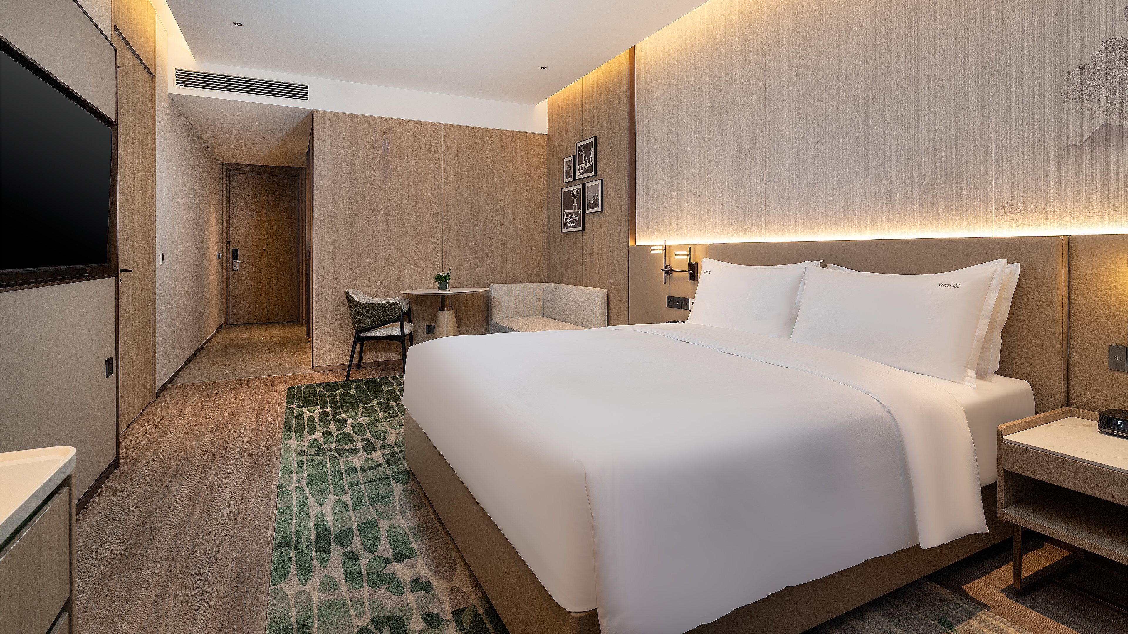 A modern hotel room with a large bed, a desk, and a chair.
