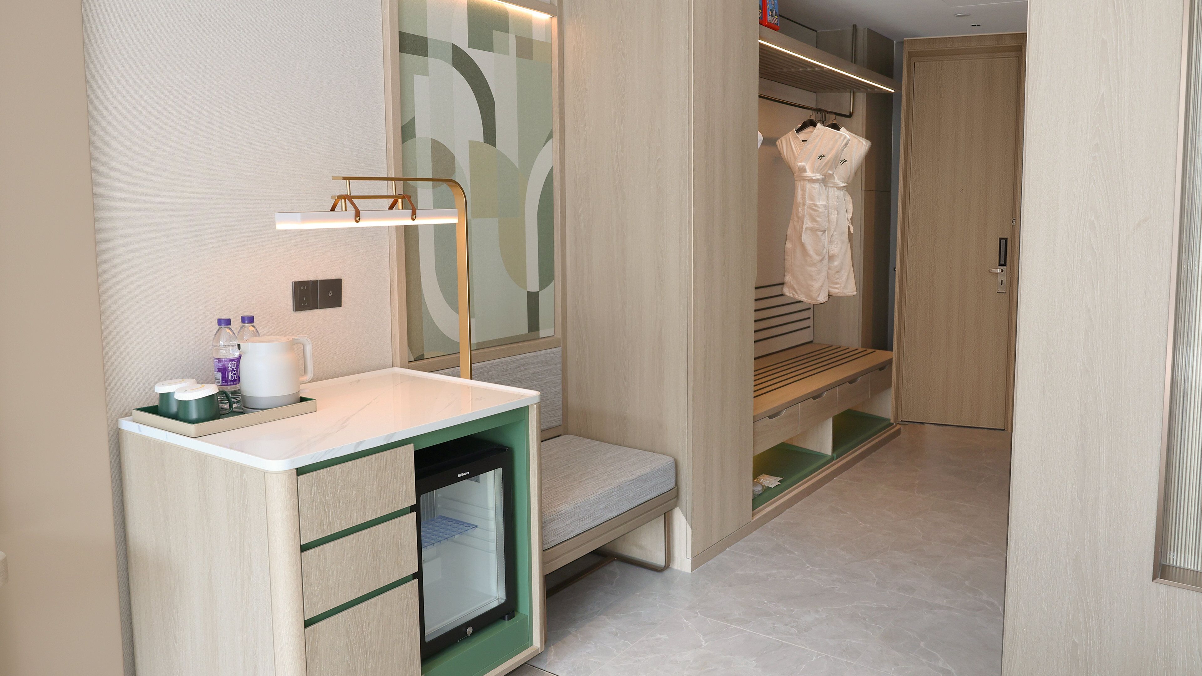 Een moderne badkamer met een wastafelmeubel, een bankje en een inloopkast met daarin opbergruimte voor gewaden.