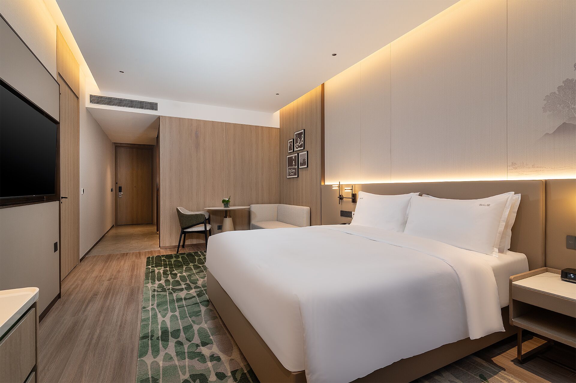 Ein modernes Hotelzimmer mit einem großen Bett, Nachttischen, einem Schreibtisch und einem Fernseher.