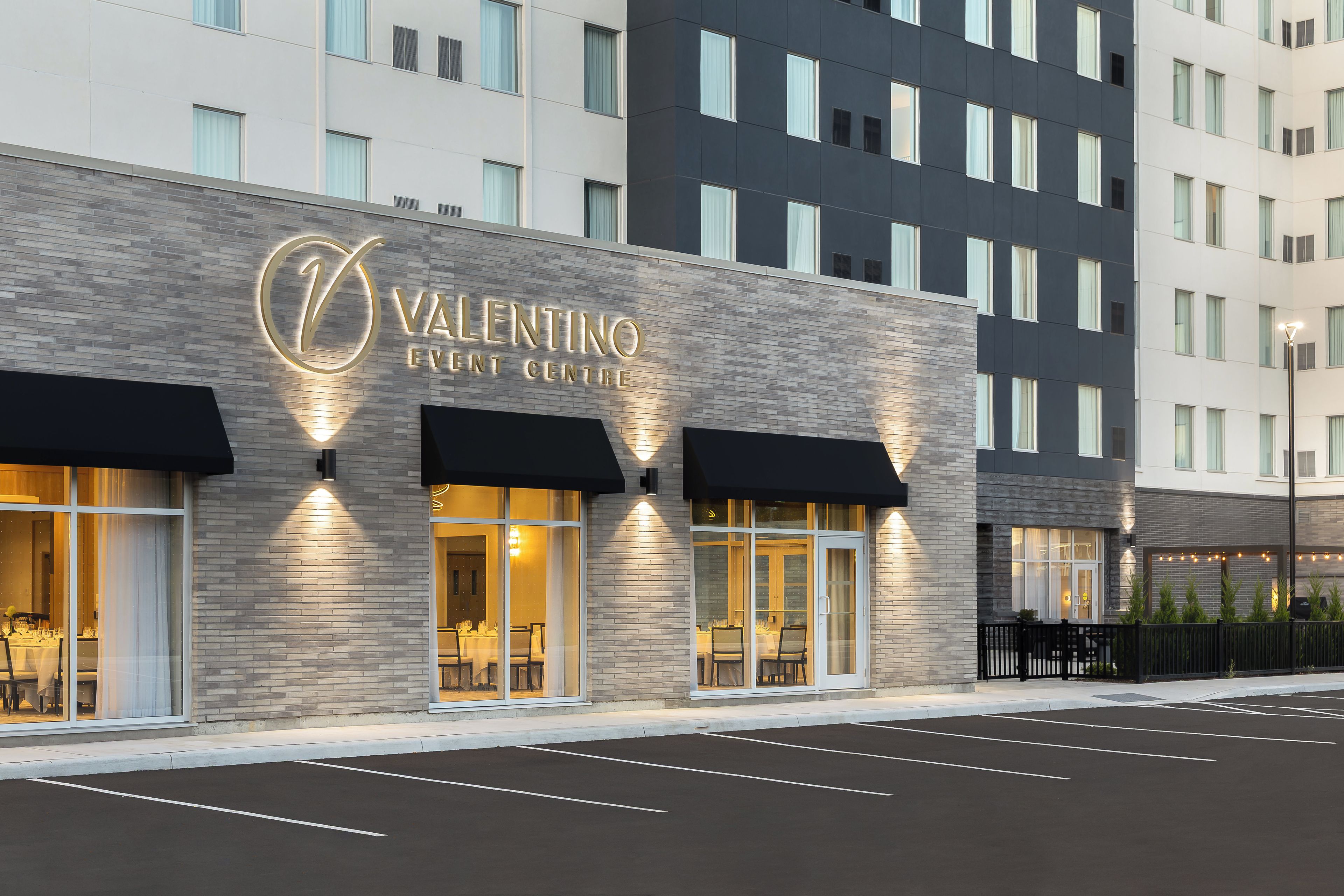 A building with a sign reading 'Valentino Event Centre' and large windows with black awnings.