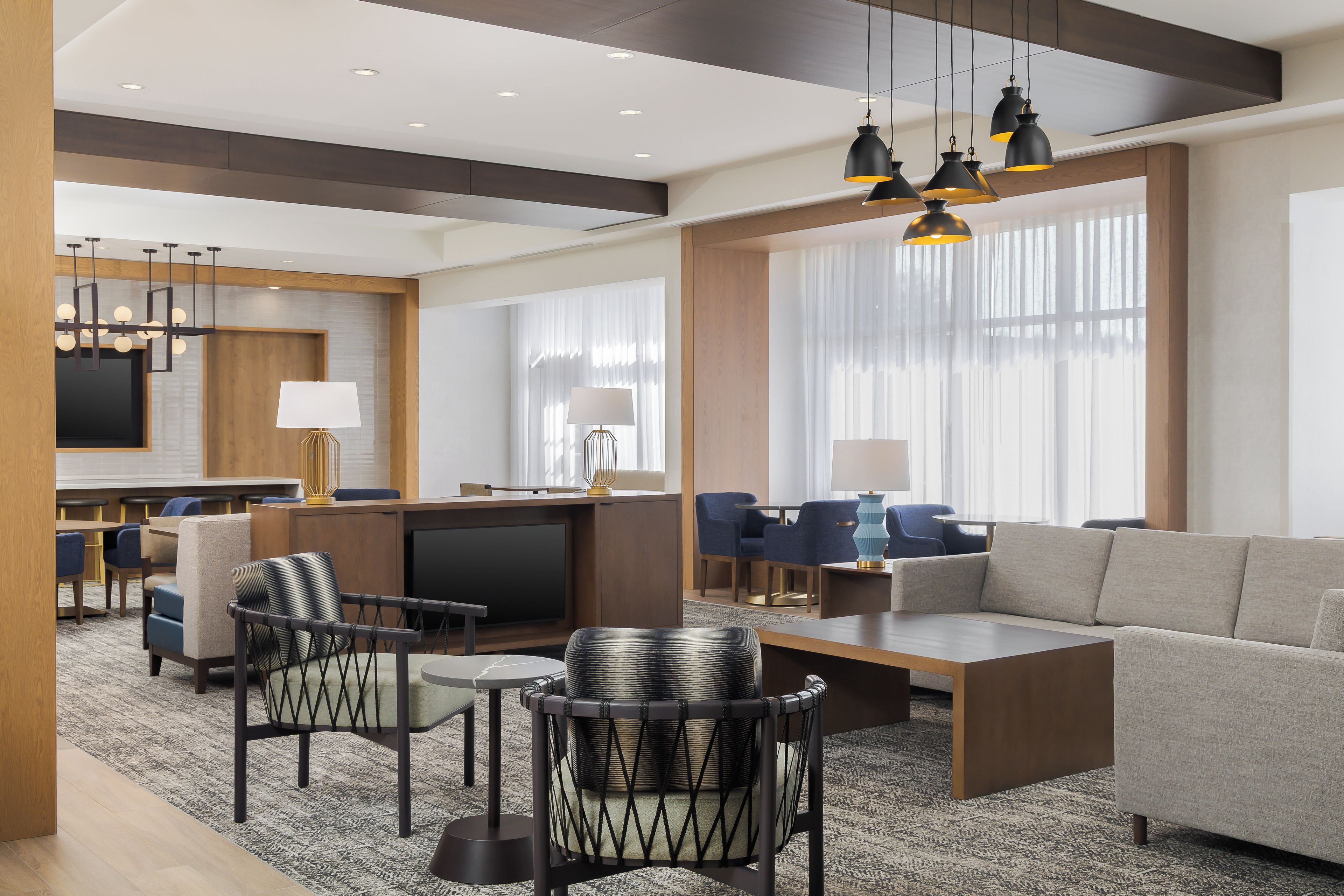 Un moderno vestíbulo de hotel con un área de estar, un bar y un televisor.