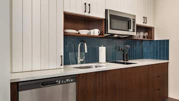 Een moderne keuken met houten kastjes, een RVS vaatwasser, een magnetron en een spoelbak met kraan.