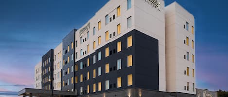 Un hôtel à plusieurs étages, doté d’un design moderne, avec un toit plat et une variété de styles de fenêtres.