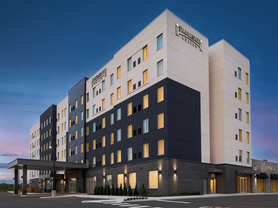 Un hôtel à plusieurs étages, doté d’un design moderne, avec un toit plat et une variété de styles de fenêtres.