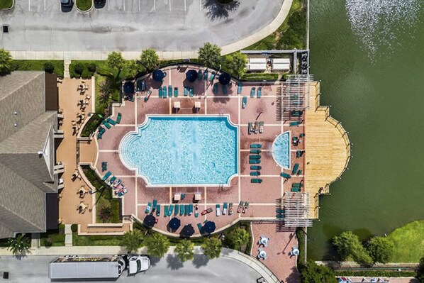 Vue aérienne d’un complexe hôtelier doté d’une piscine centrale, d’espaces de détente et d’un quai au bord de l’eau.