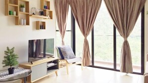 A modern living room with a flat-screen TV, wooden shelves, a small table, and a chair. - Electus Home at Midhills Genting - Free WiFi & Parking (Genting Highlands)