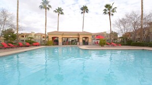 A swimming pool with red lounge chairs and palm trees. - Gilbert/Mesa 2 Bedroom Condo, right next to heated pool! (Mesa)