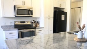 A modern kitchen with white cabinets, stainless steel appliances, and a marble countertop. - Gilbert/Mesa 2 Bedroom Condo, right next to heated pool! (Mesa)