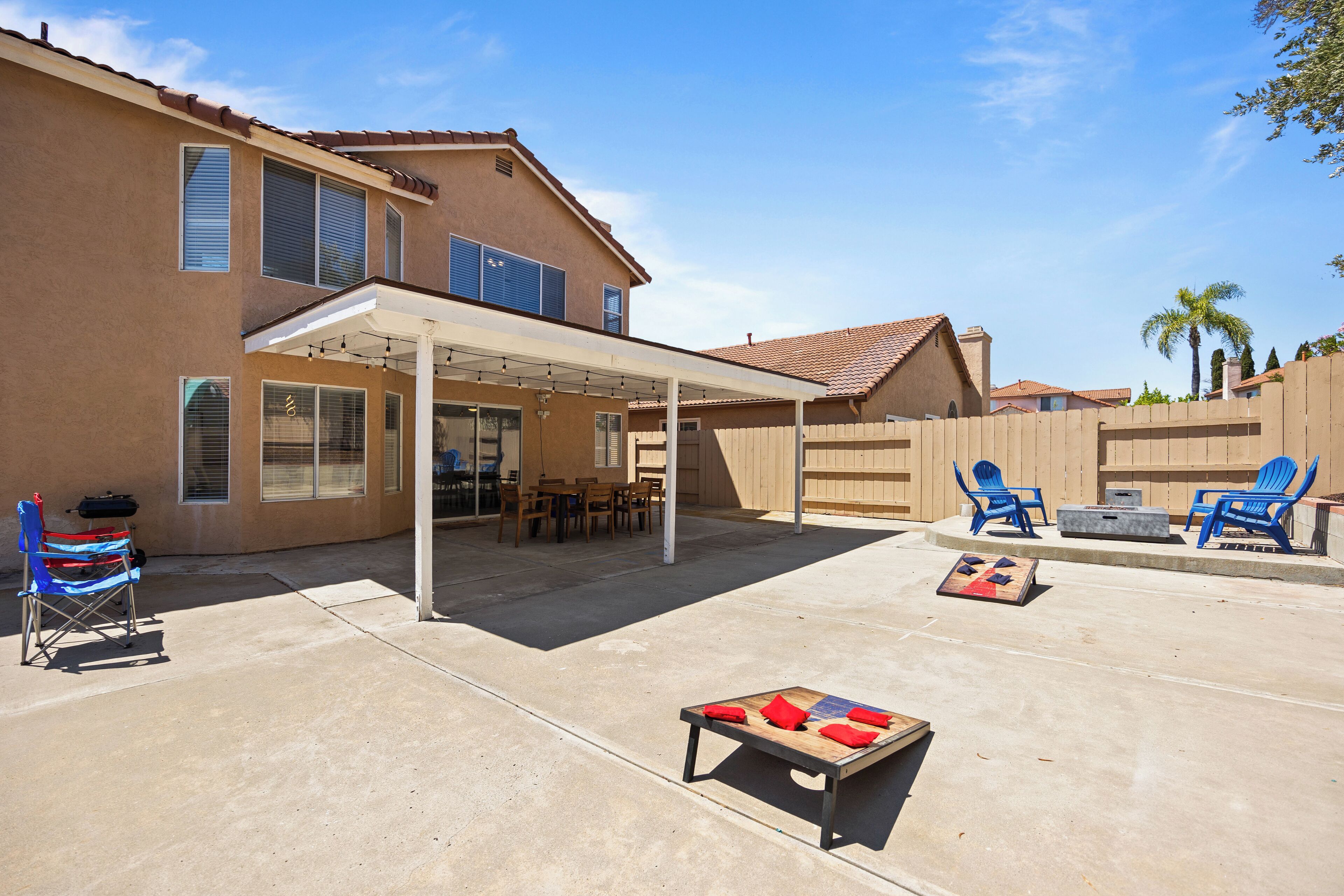A covered patio area with outdoor furniture, a table with cushions, and a pool table.