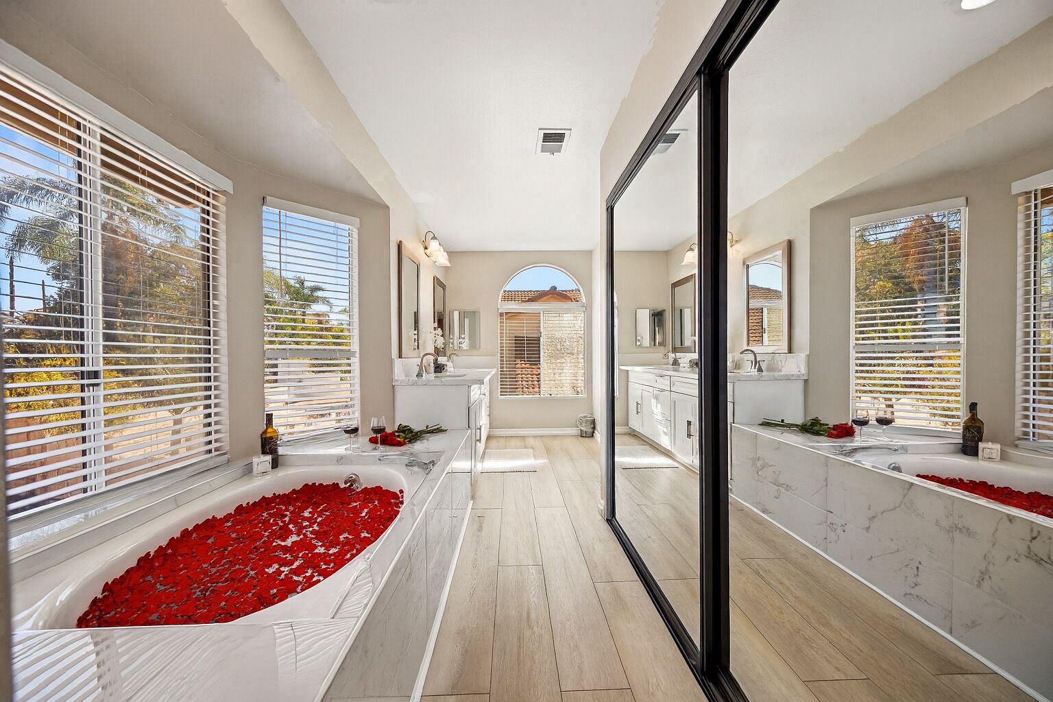 A modern bathroom with a large bathtub, two sinks, and a shower area.