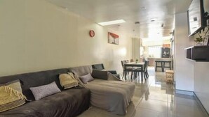 A living room with a sofa, a dining table, and chairs. - For 6, NO stairs, beach, Costco, well located! (Mérida)