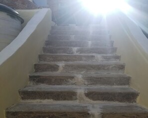 A set of stone steps leading upwards, surrounded by walls, with a bright light source at the top.