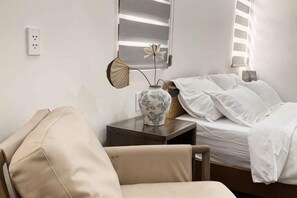 A hotel room with a bed, a chair, a bedside table with a lamp, and a vase. - Signy House City Center (Ho Chi Minh City)