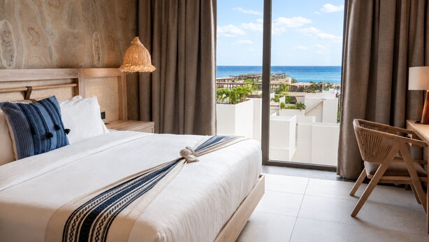 A hotel room with a large bed, a desk, and a view of the ocean. - Hotel Indigo Playa Del Carmen by IHG (Playa del Carmen)