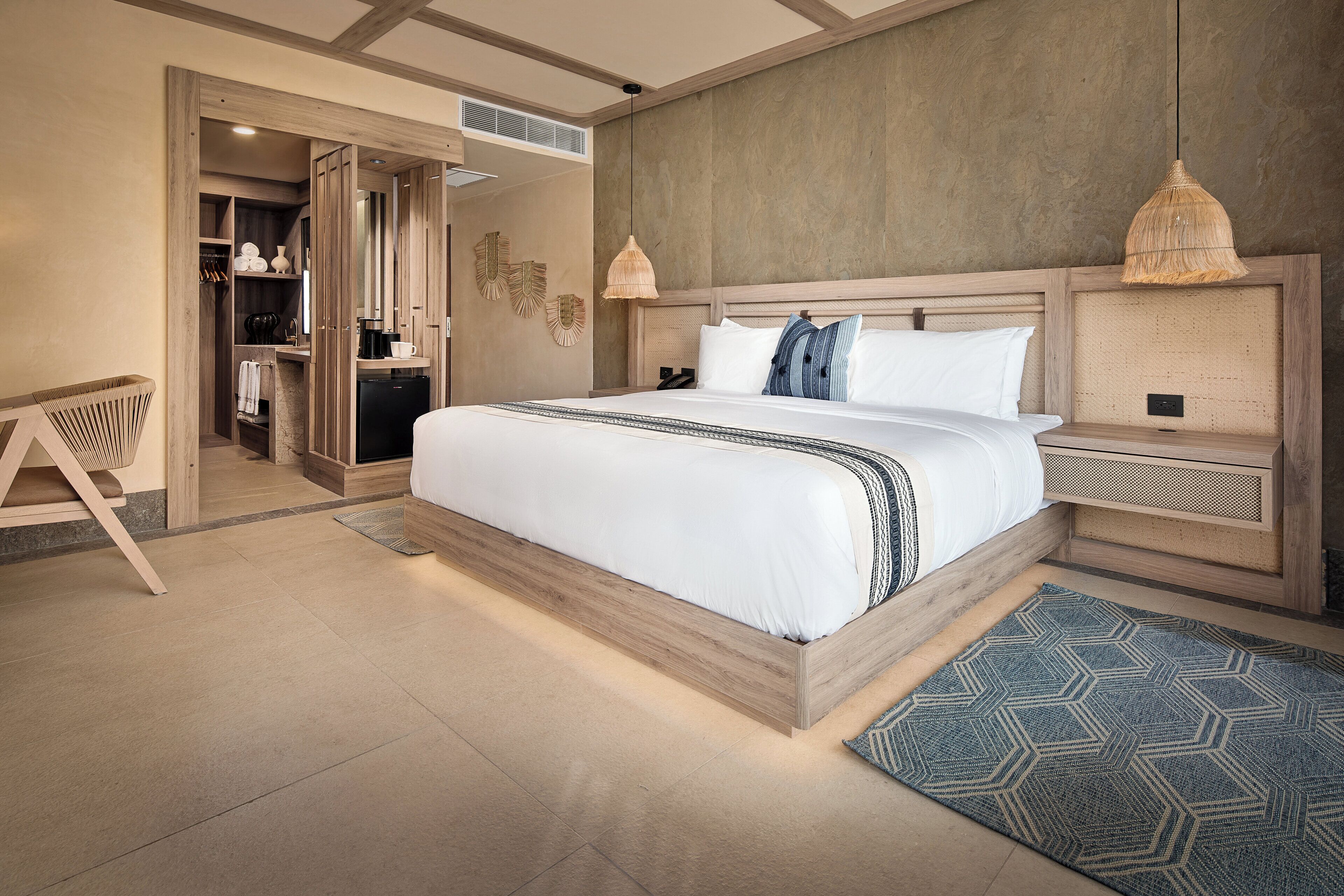 A bedroom with a large bed, wooden headboard, bedside tables, a wardrobe, and a hanging light fixture.