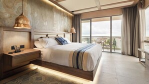 A modern hotel room with a large bed, a bedside table with a phone, a hanging lamp, and a view of the city through large windows. - Hotel Indigo Playa Del Carmen by IHG (Playa del Carmen)