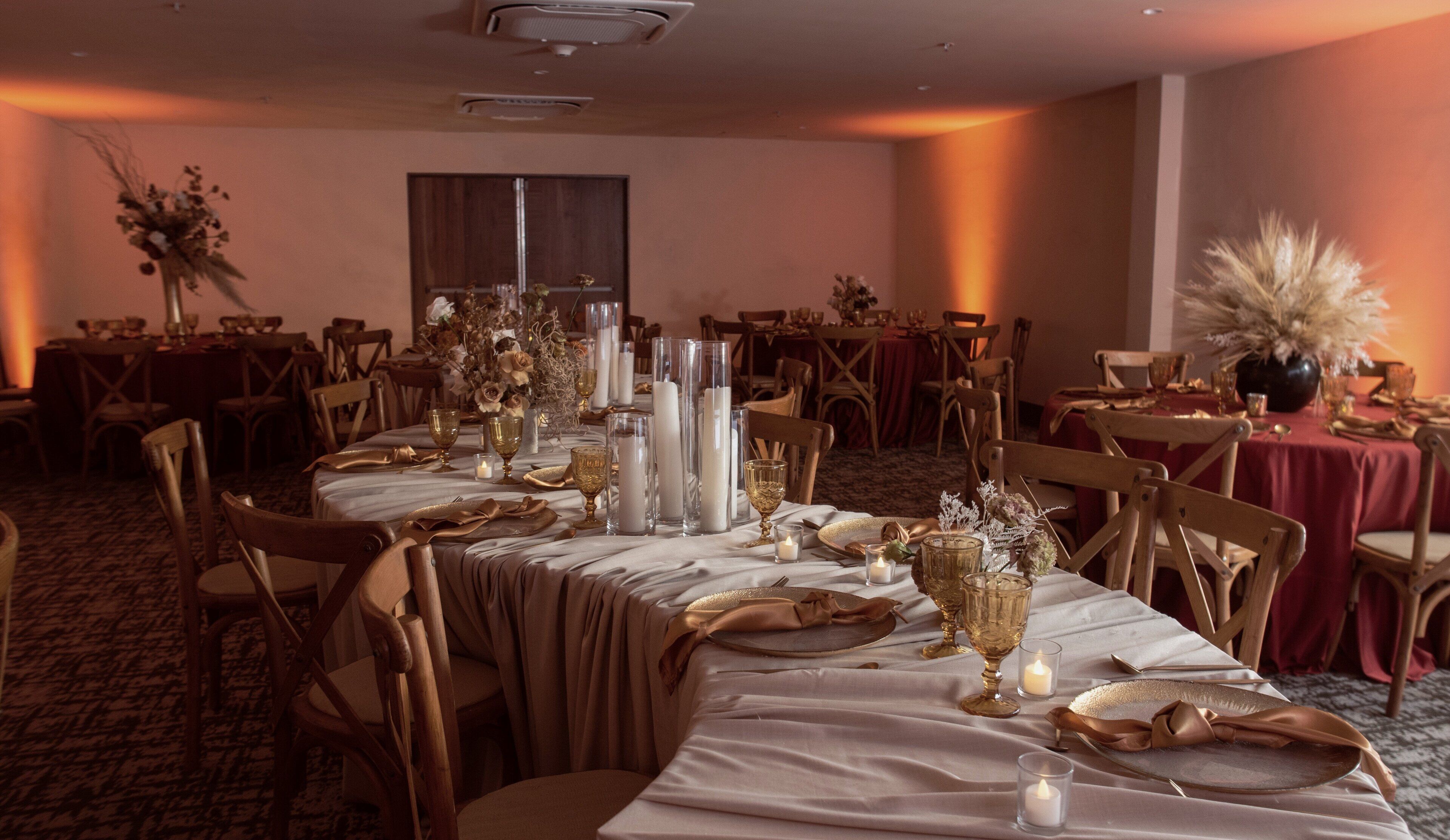 A banquet hall with round tables, white tablecloths, and gold accents.