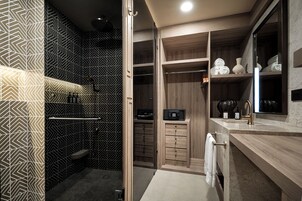 Un baño moderno con un muro de patrón geométrico, un tocador de madera y una zona de ducha integrada.