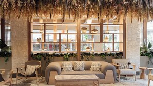 A modern living room with a sofa, armchairs, a coffee table, and a decorative wall with shelves. - Hotel Indigo Playa Del Carmen by IHG (Playa del Carmen)