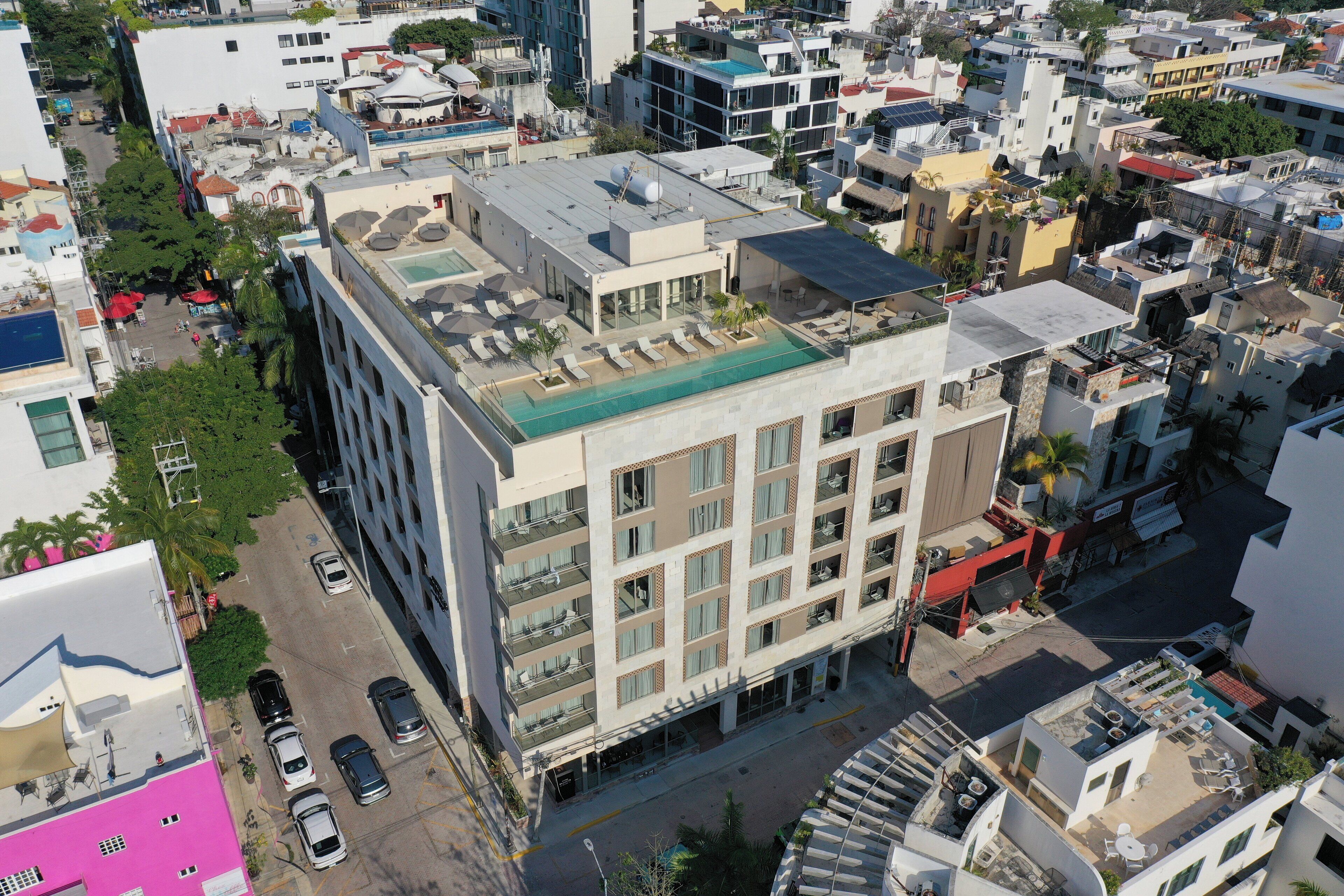 A multi-story building with a rooftop pool, multiple balconies, and a street view.