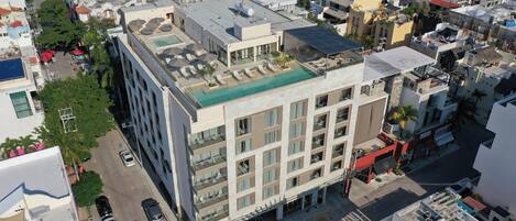 A multi-story building with a rooftop pool, multiple balconies, and a street view.