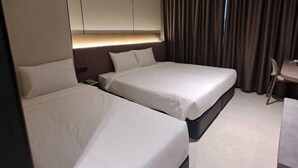 Hotellihuone, jossa on kaksi sänkyä, työpöytä ja suuri ikkuna, jossa on verhot.