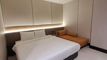 A modern bedroom with a large bed, a bedside table, a nightstand, and a sofa.