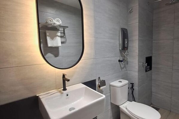 A modern bathroom with a white sink, toilet, and shower. - Urban Inn Myra Meranti (Puchong)