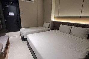 A hotel room with two single beds, a desk, and a door with an air conditioning unit. - Urban Inn Myra Meranti (Puchong)