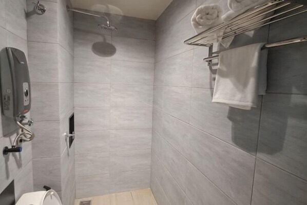 A modern bathroom with a shower, toilet, and towel rack. - Urban Inn Myra Meranti (Puchong)