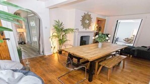 A modern living room with a wooden dining table, a fireplace, and a large mirror on the wall. - Bagend Sleeps 14 Hot Tub Balcony & Ping Pong (North Devon District)