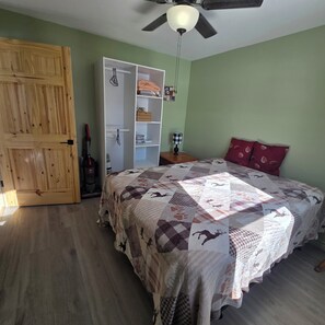 Una camera da letto con un letto, un armadio, una ventola a soffitto e un comodino.