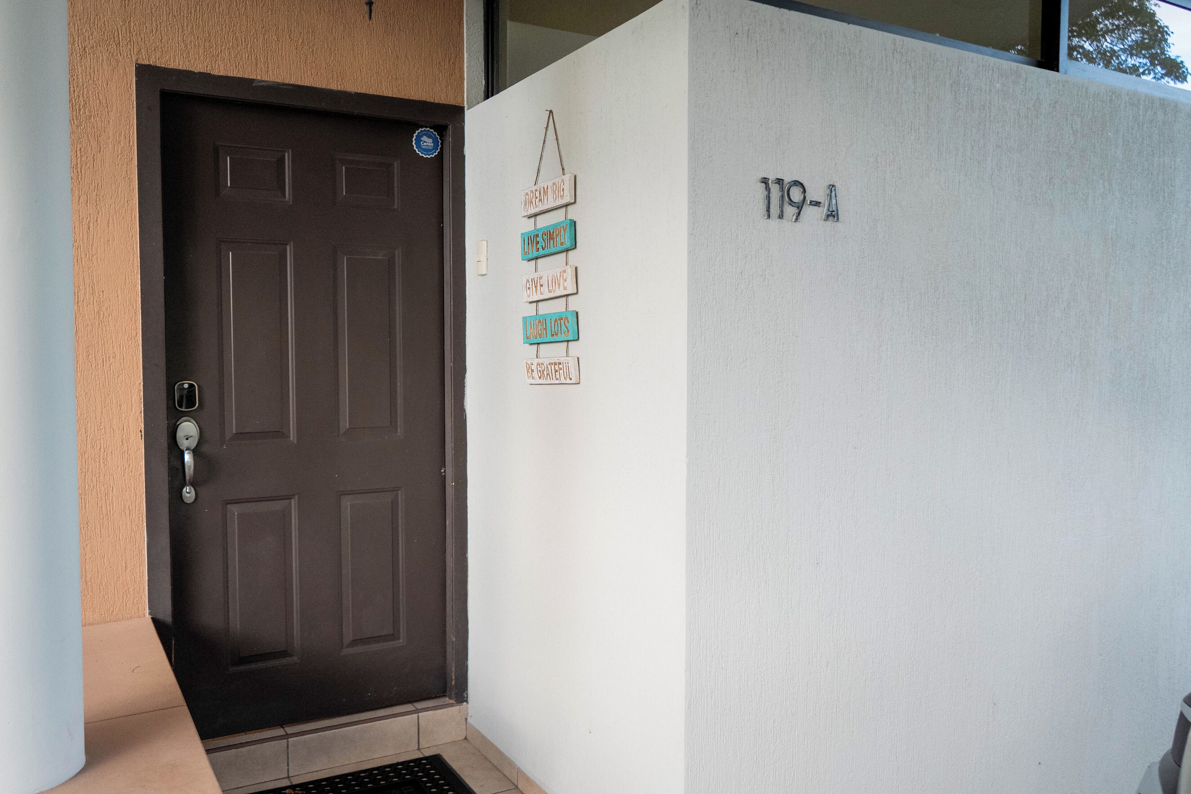 A door with a keypad lock and a wall sign with motivational phrases.