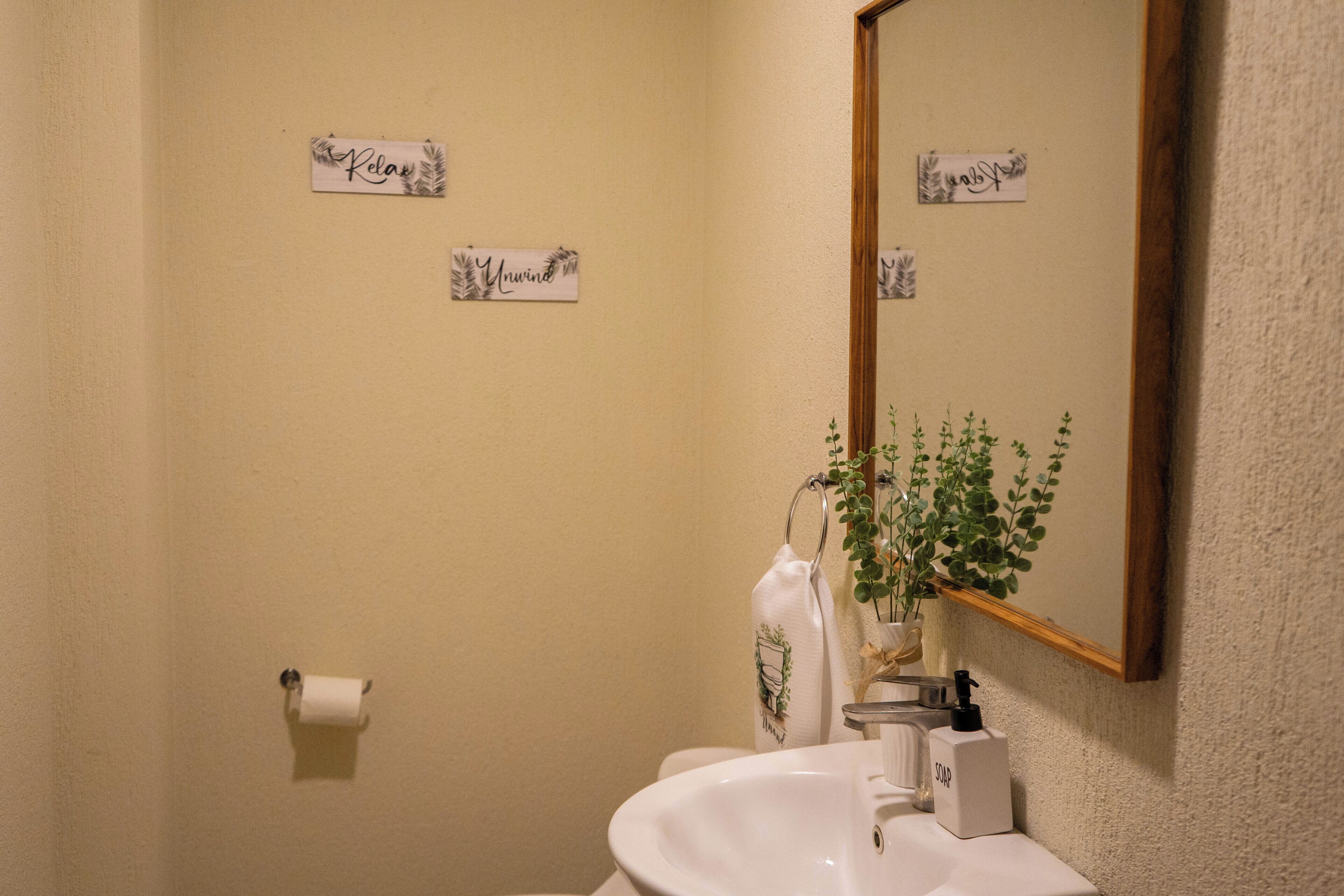 Une salle de bain avec un lavabo, un miroir et deux panneaux affichés sur le mur.