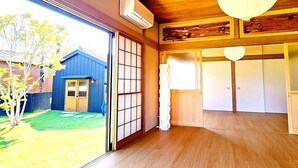 Une pièce dotée d’une porte coulissante, d’un plancher en bois, d’un ventilateur de plafond et offrant une vue sur un immeuble bleu à l’extérieur.
