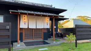 Un bâtiment japonais traditionnel doté d’une entrée en bois, de tatamis et d’un petit jardin.