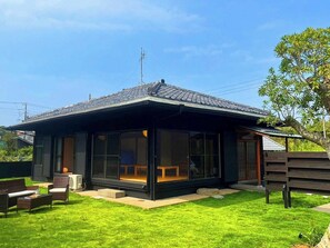 Une maison moderne dotée d’une grande baie vitrée, d’une terrasse en bois et d’une pelouse bien entretenue.