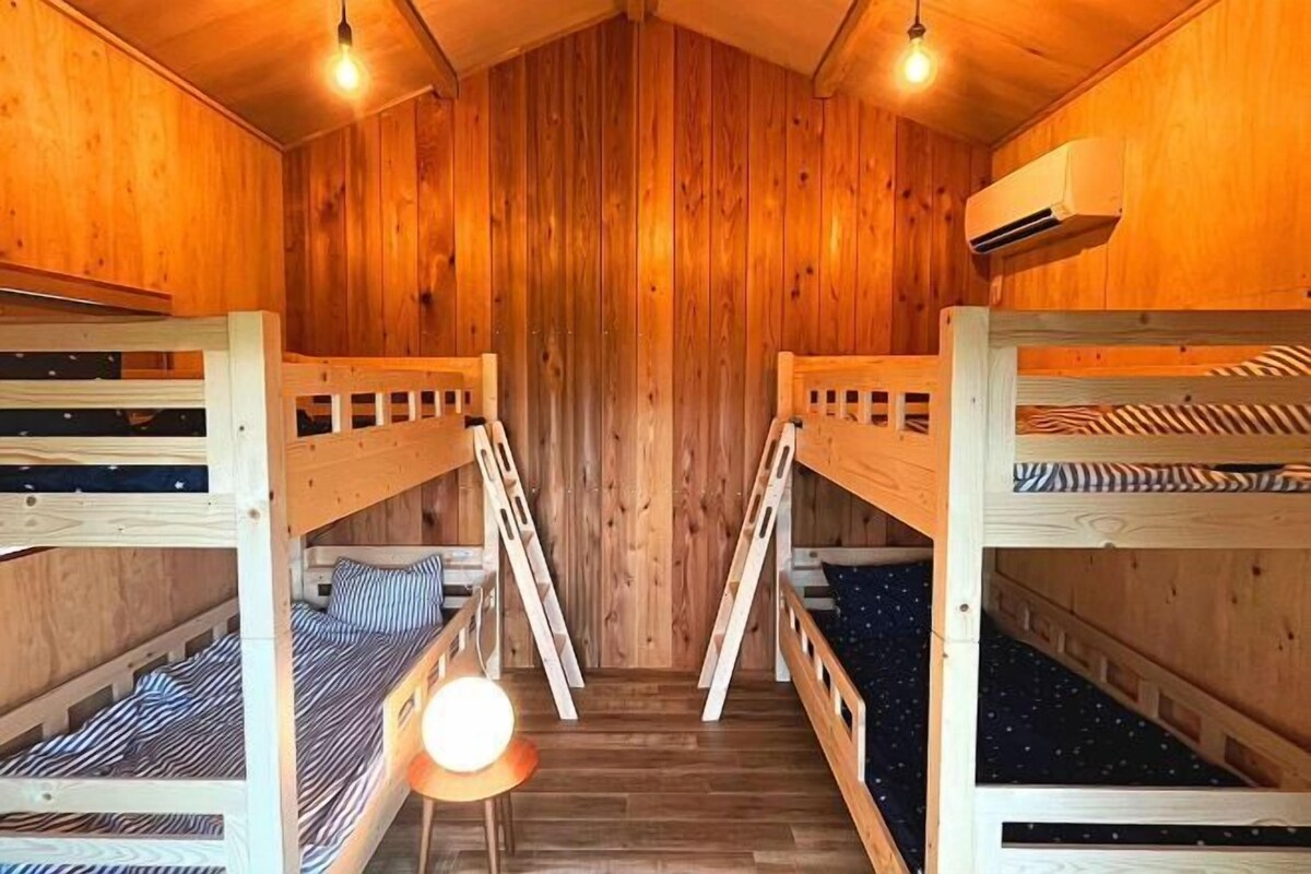 Une cabane en bois avec des lits superposés, un luminaire central et un appareil de climatisation.
