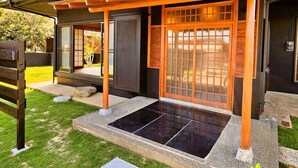 Une maison traditionnelle japonaise avec une entrée en bois, des portes coulissantes et un espace d’entrée carrelé en pierre.